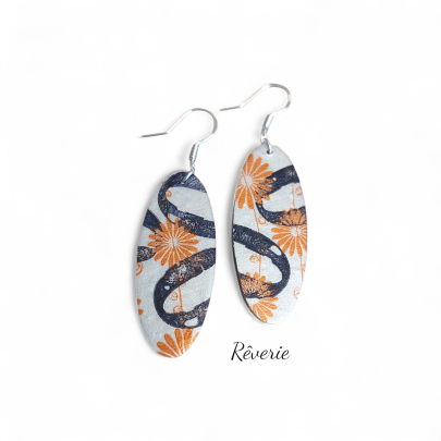 Whimsy meets structure. These marquise-shaped polymer clay earrings feature burnt-orange daisies orbiting dark abstract loops on a shimmering pale base.